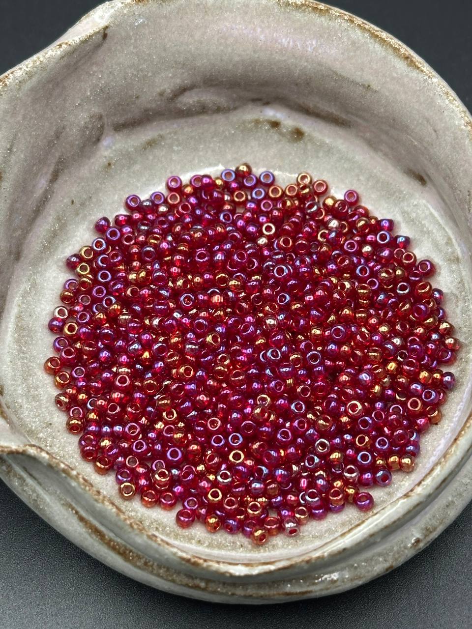 Small container filled with red and pink beads on a gray background