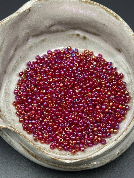 Small container filled with red and pink beads on a gray background