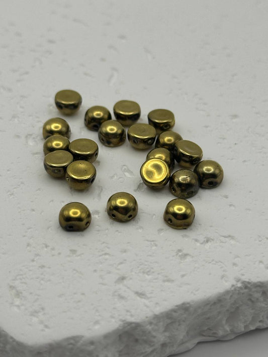 Gold colored cabochons on a textured white surface