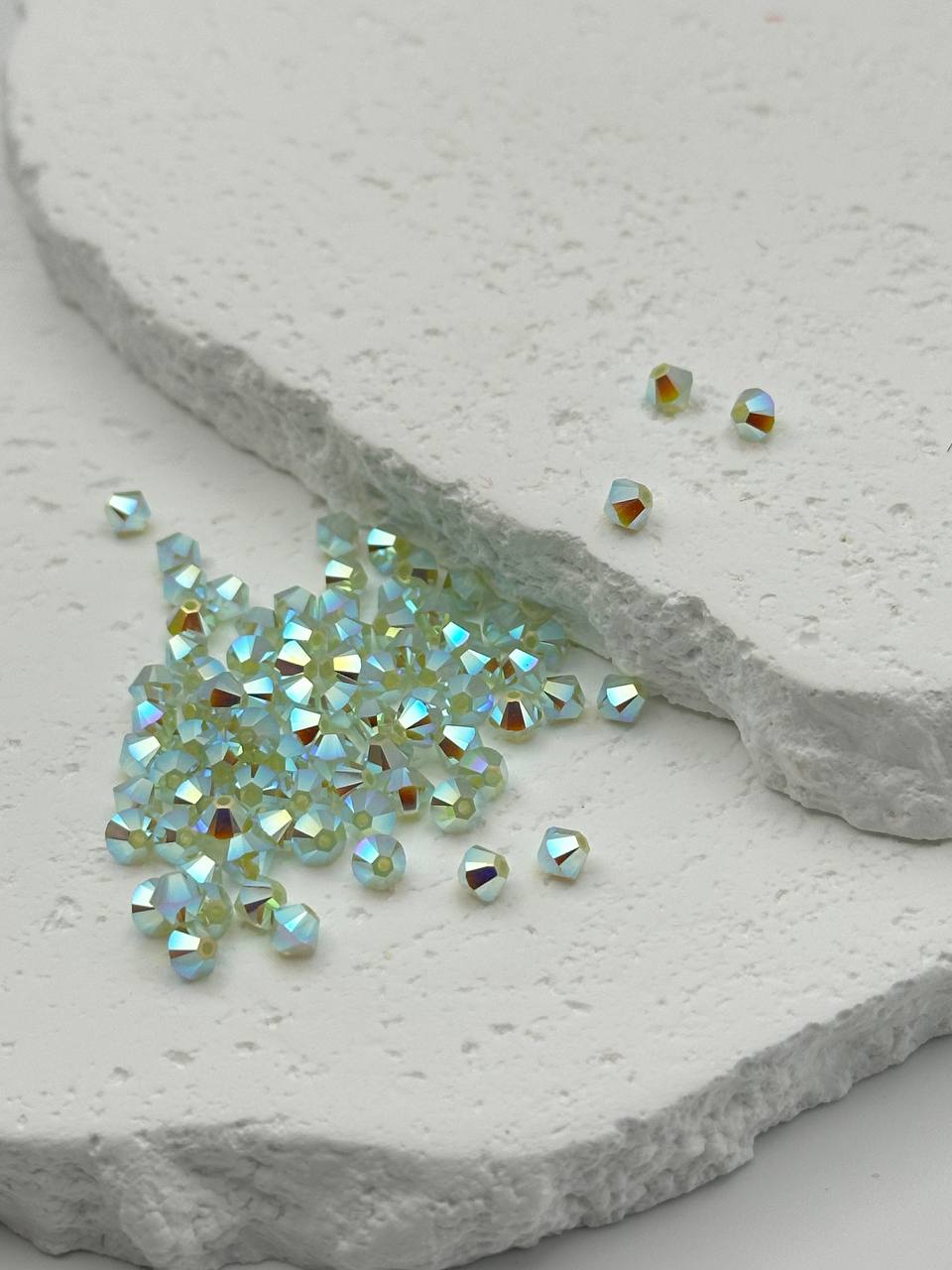 Small chrysolite bicone beads on a light stone surface