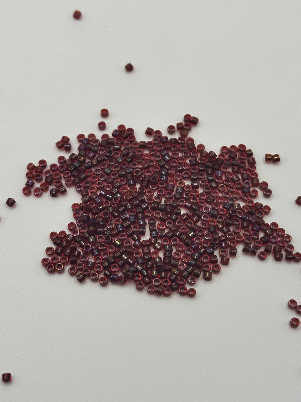 Small red beads scattered on a light gray background