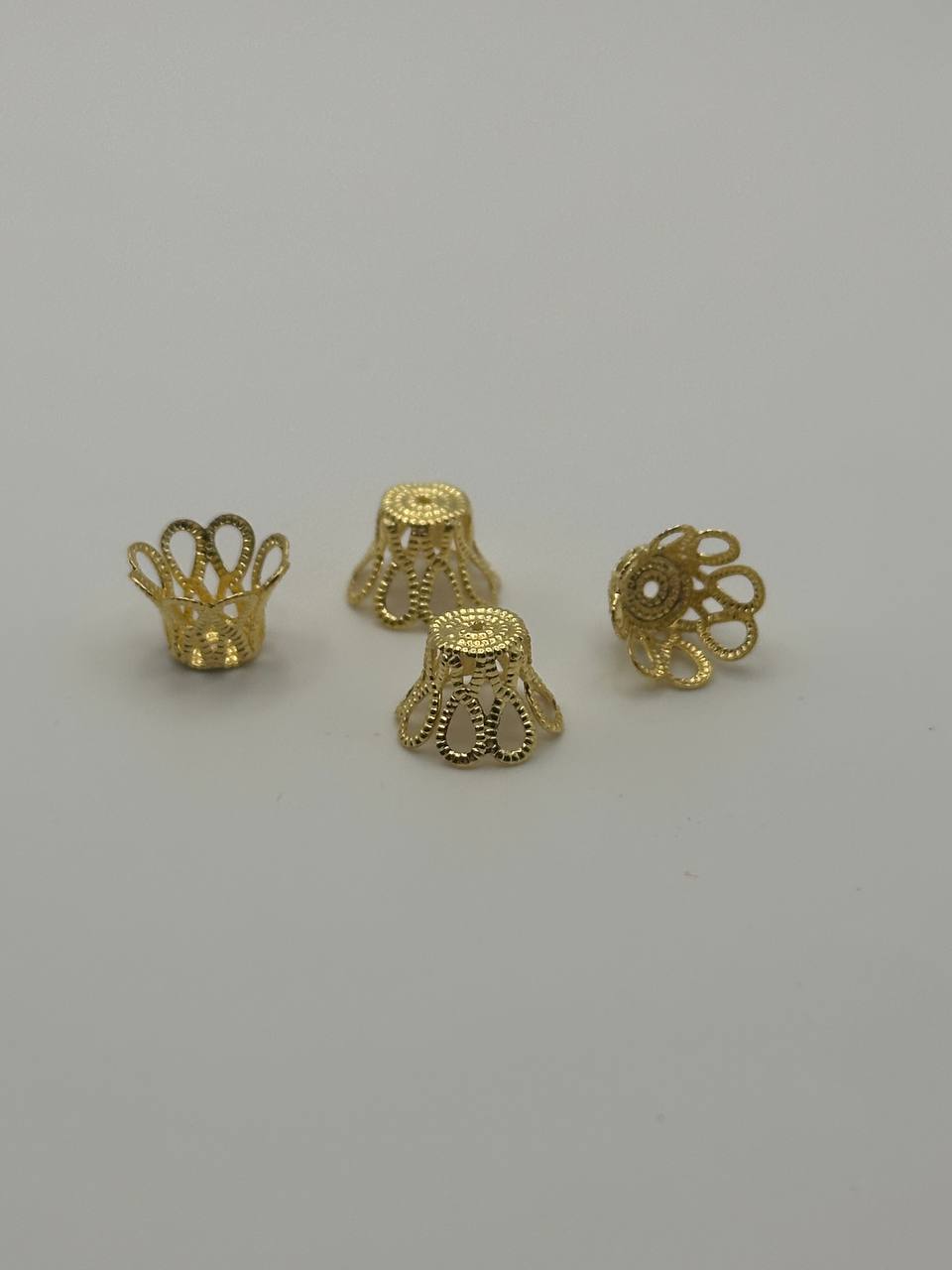 Four gold jewelry components on a gray background