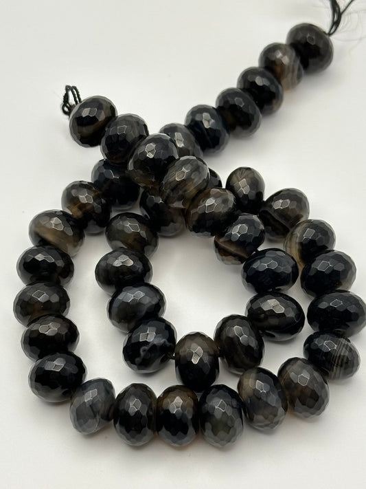 String of black faceted eye agate beads on a white background