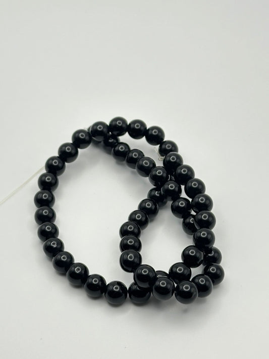 A string of black agate smooth round beads on a white surface