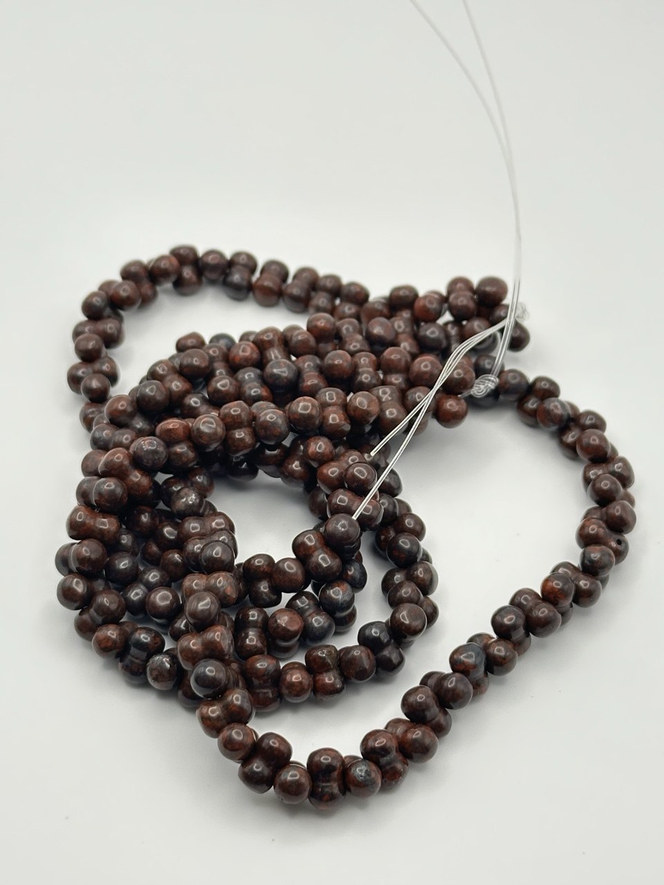 String of dark brown double beads on a white background