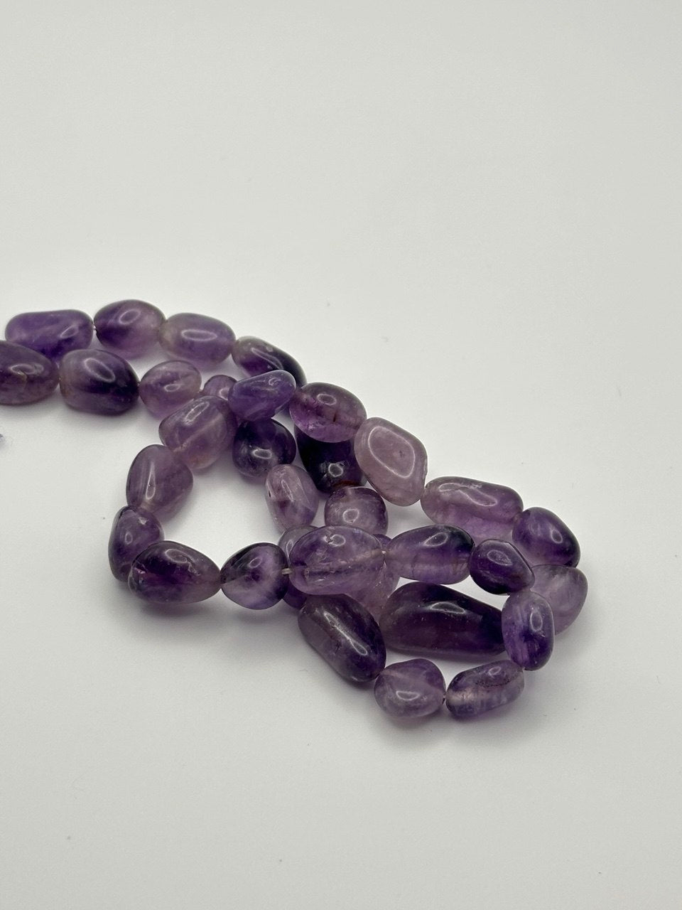 A string of nugget amethyst beads on a white surface