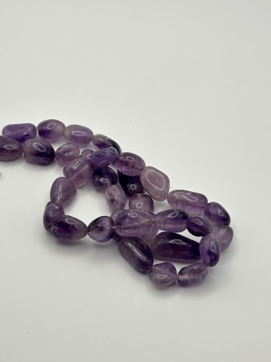 A string of nugget amethyst beads on a white surface