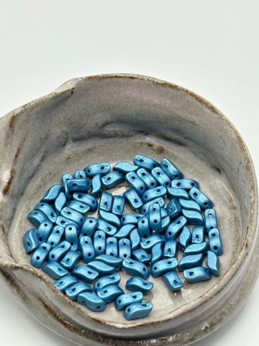 Blue ceramic beads in a gray pot on a white background