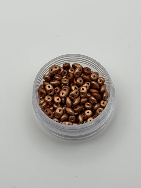 Clear container filled with small metallic beads on a light gray background