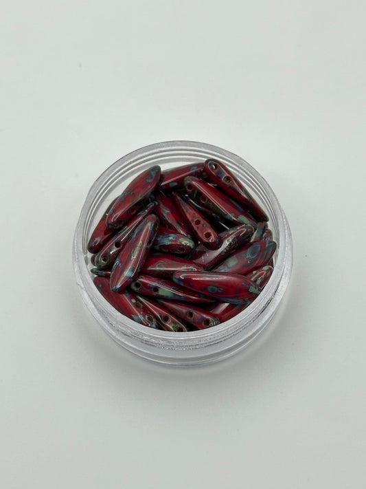Clear container with red and black dagger beads on a light gray background