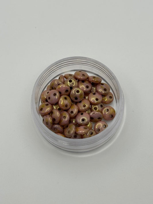 Small clear container filled with round 2-hole rose gold beads on a white background