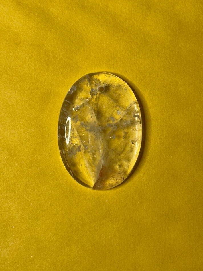 clear quartz pendant on yellow surface