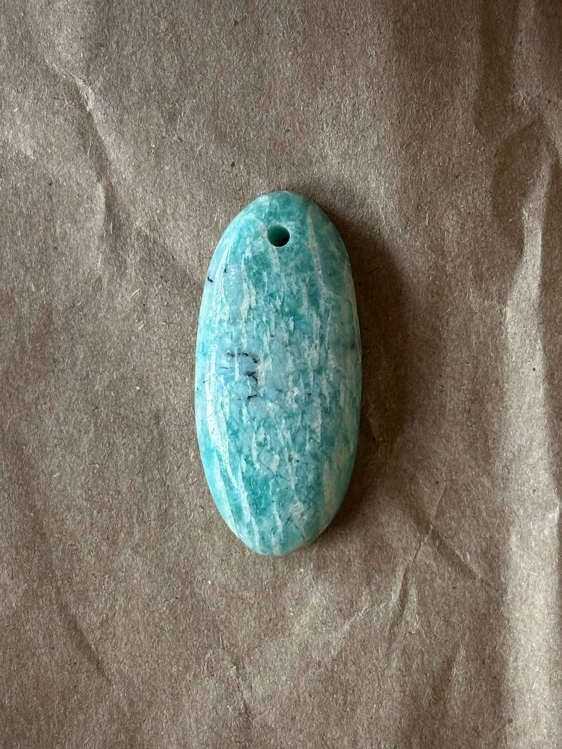 Amazonite oval cabochon with luster on brown paper background