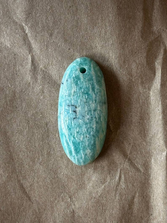 Amazonite oval cabochon with luster on brown paper background