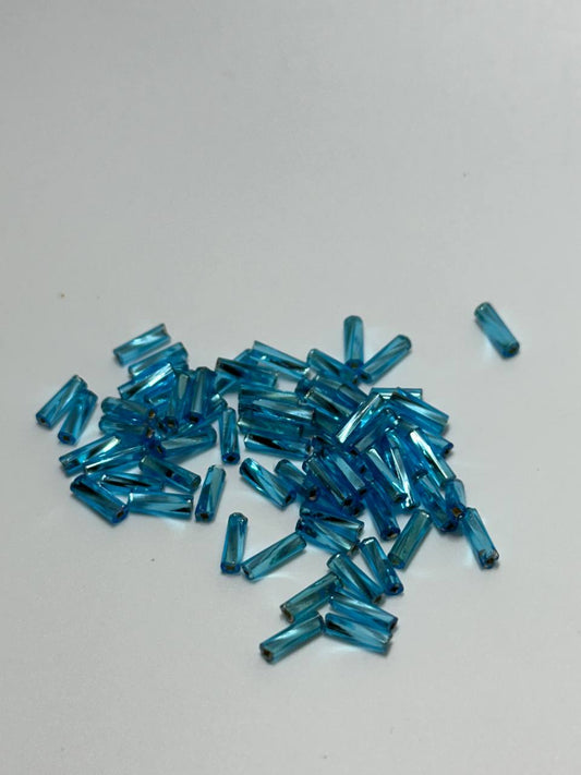 A small pile of twisted bugle beads in blue color