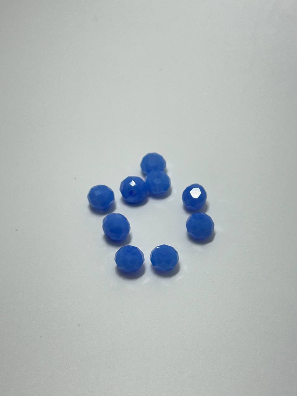 A set of nine light blue faceted rondelle beads on white background