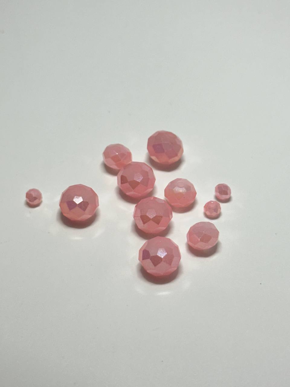 A small pile of rose AB faceted rondelle beads on white surface