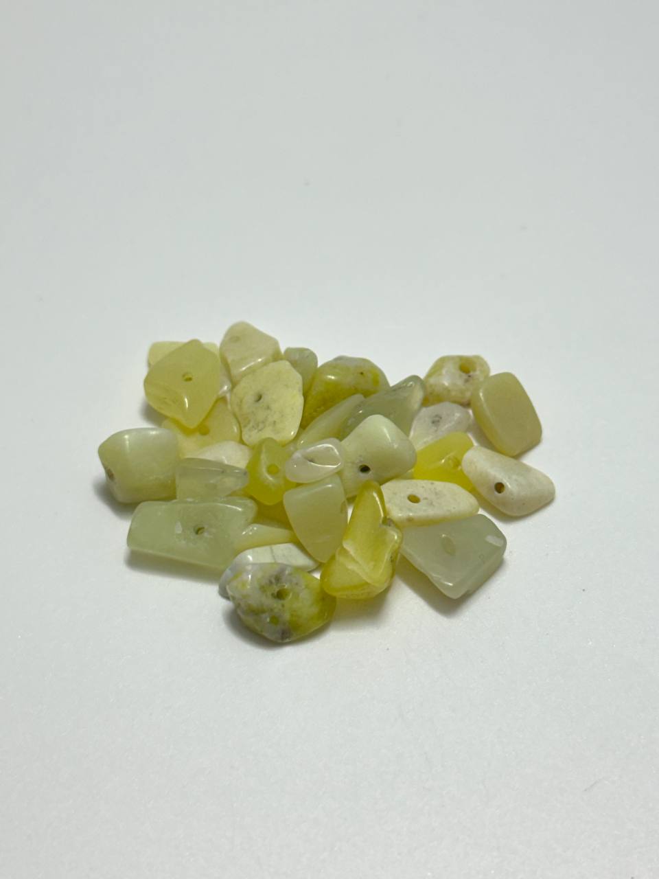 A small pile of serpentine irregular chip beads on white background
