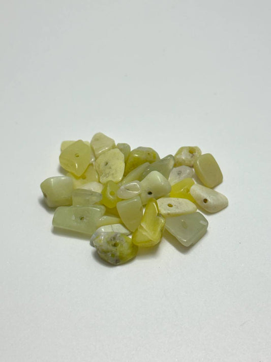 A small pile of serpentine irregular chip beads on white background