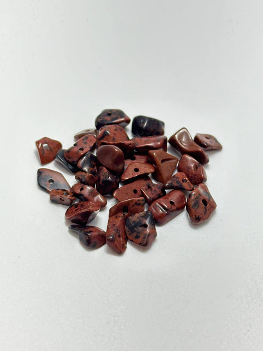 A small pile of mahogany obsidian chip beads on white background