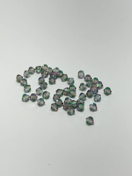 A small cluster of faceted iridescent beads scattered on a plain light gray background.