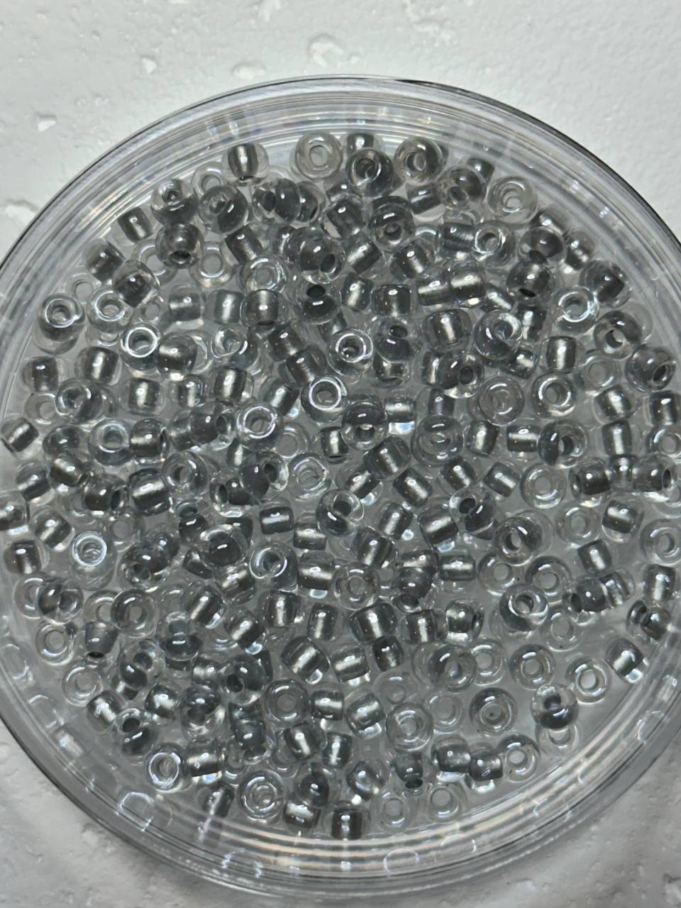 A small pile of sparkling pewter lined crystal seed beads on white surface