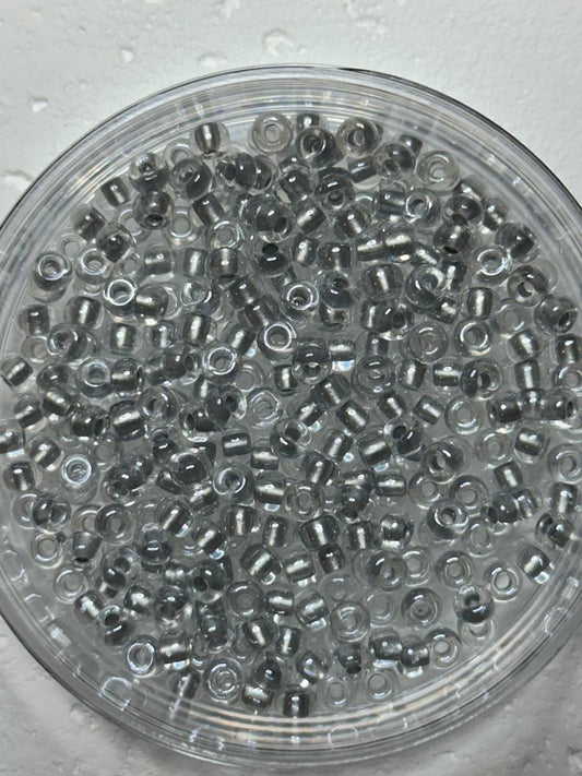 A small pile of sparkling pewter lined crystal seed beads on white surface