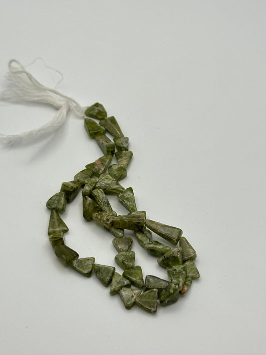 A string of olive green triangle shaped beads on a white surface