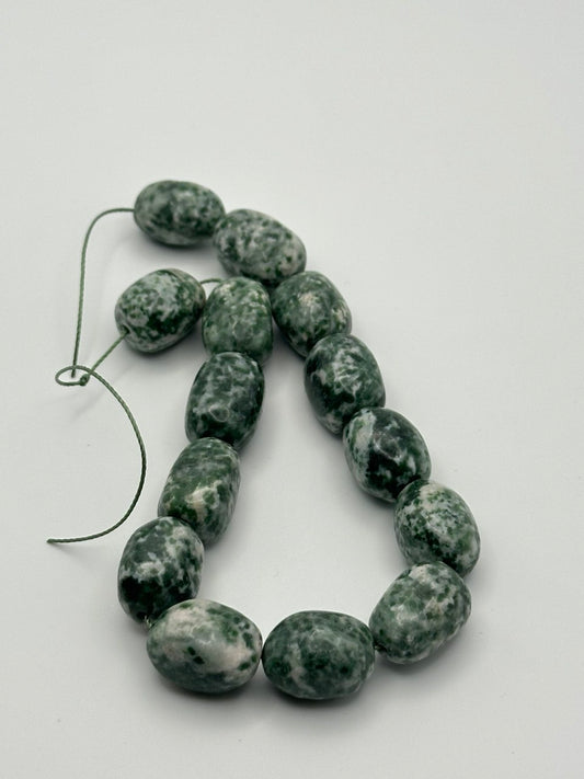 A string of tree agate bulky nugget beads on a white surface