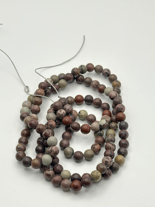 A string of greyish, light brown, and black round agate beads on a white surface