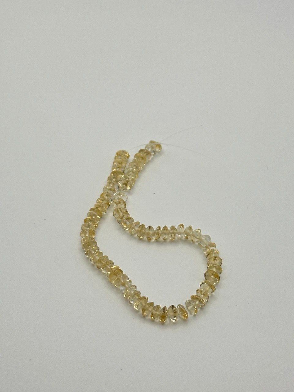 A string of crystal yellow citrine rondelle beads on a white surface