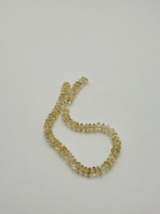 A string of crystal yellow citrine rondelle beads on a white surface