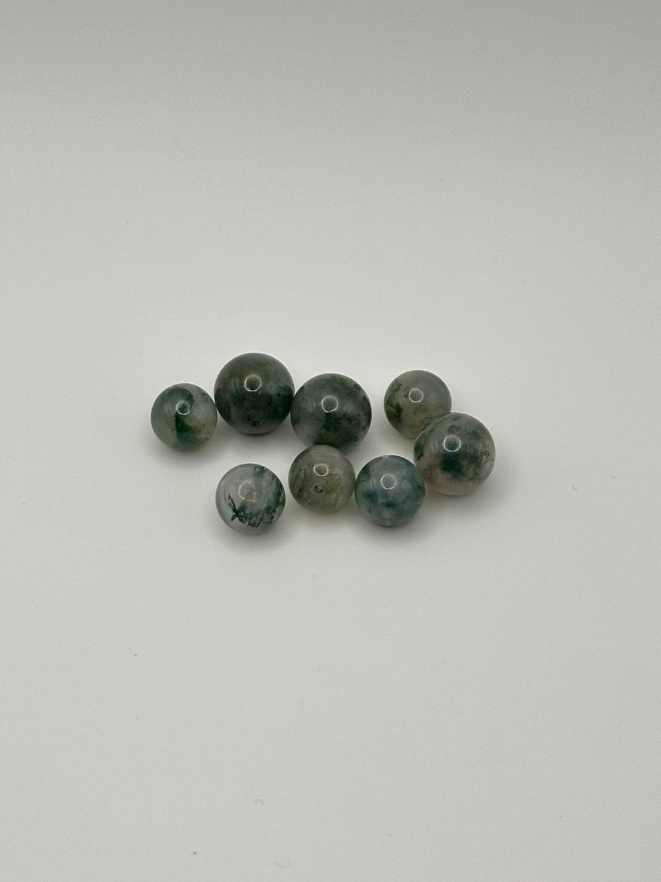 Set of multicolor green beads on a white background