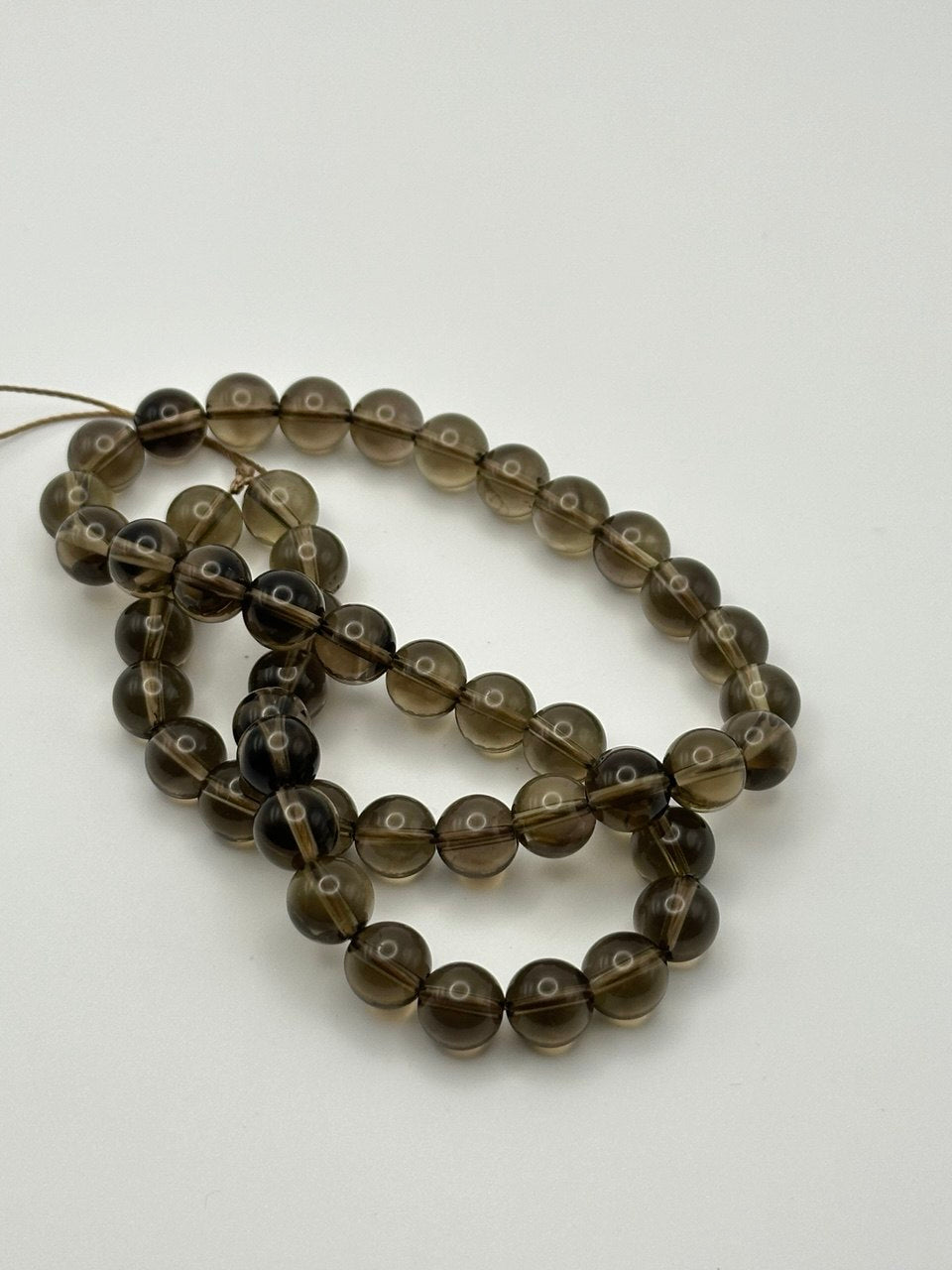 A string of transparent round smoky quartz beads on a white surface