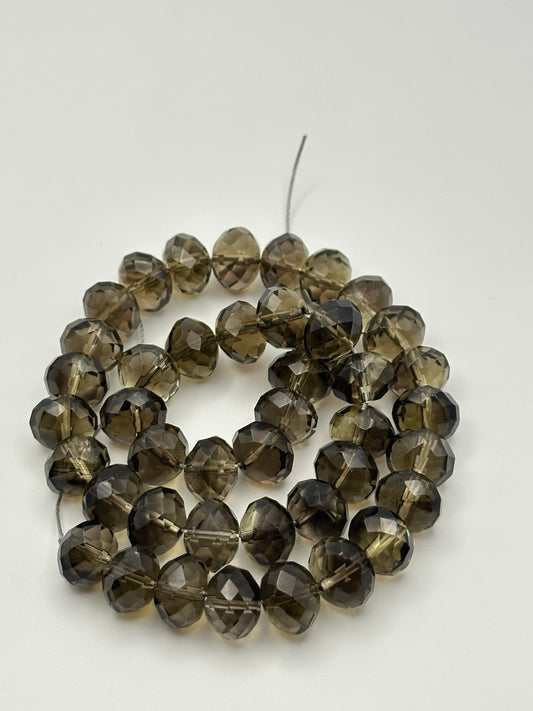 A string of faceted rondelle smoky quartz beads on a white surface