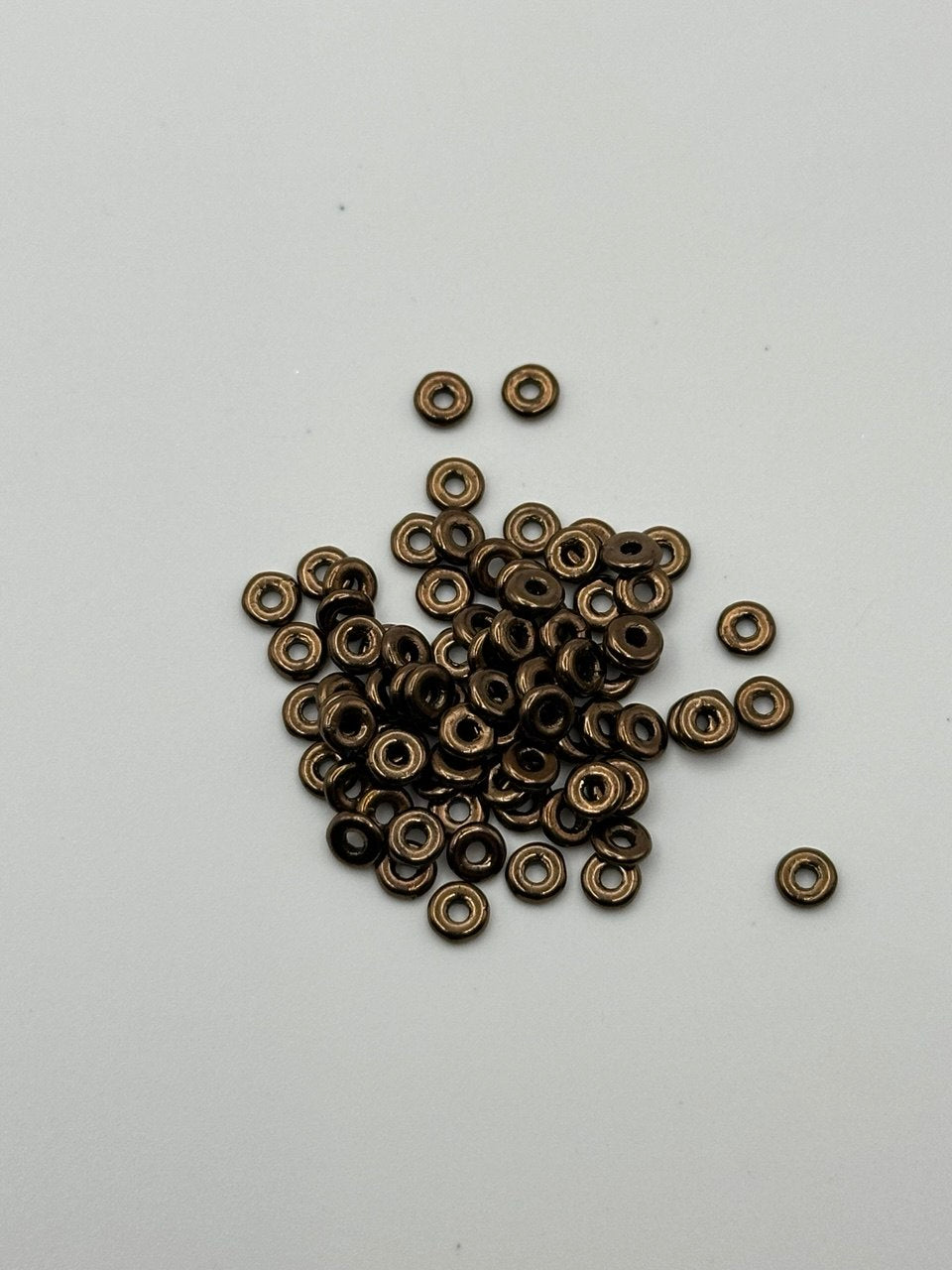 Small bronze metal O beads on a white background