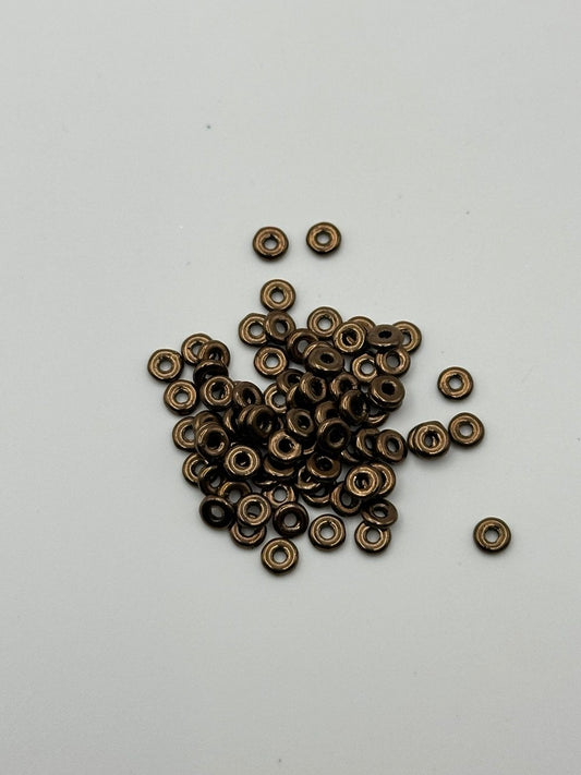 Small bronze metal O beads on a white background