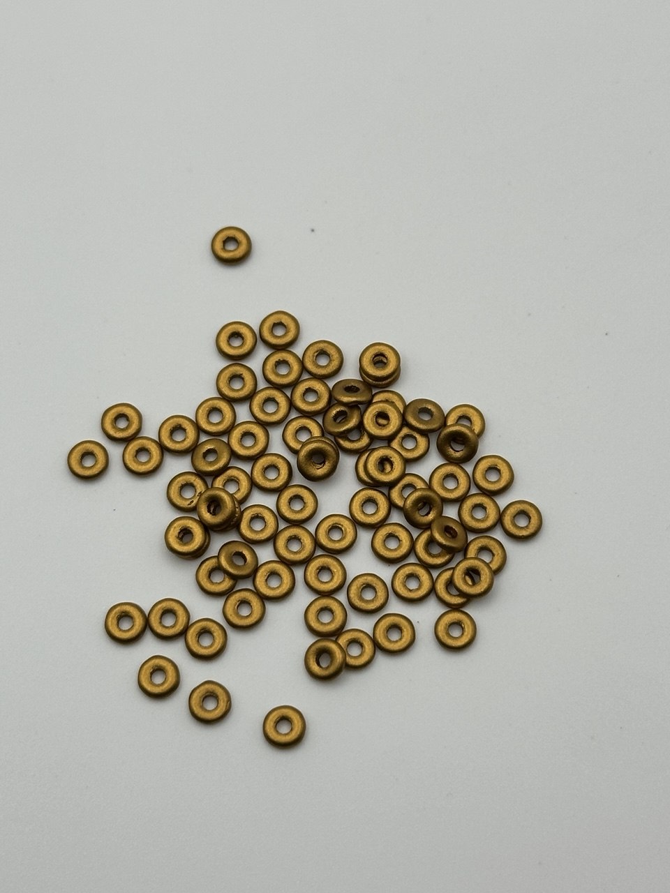 Small gold metal O beads on a white background