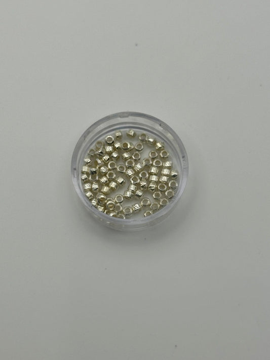 Small container filled with small metallic crimp beads on a gray background