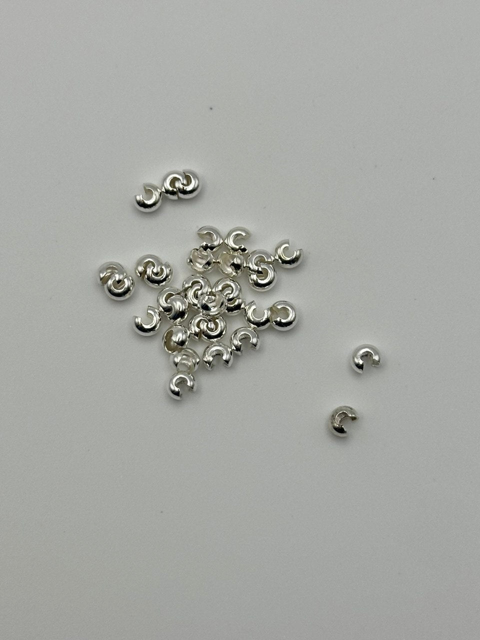 Silver jewelry components on a light gray background