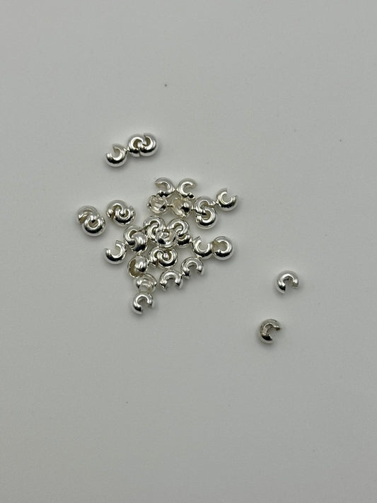 Silver jewelry components on a light gray background