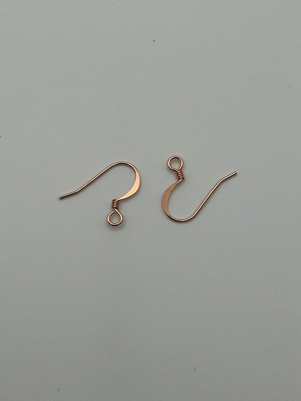 Two copper earring hooks on a gray background