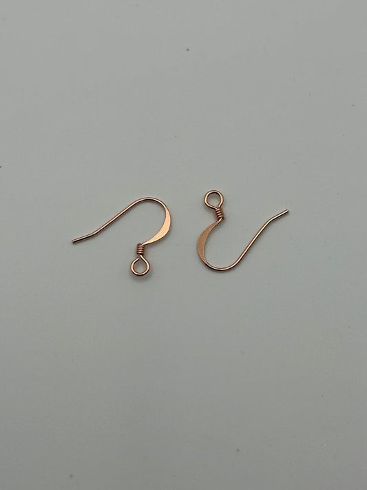 Two copper earring hooks on a gray background