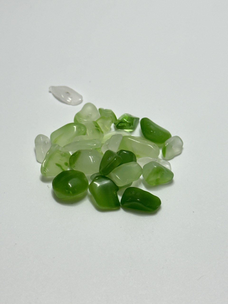 A small pile of grossular garnet chip beads on white background