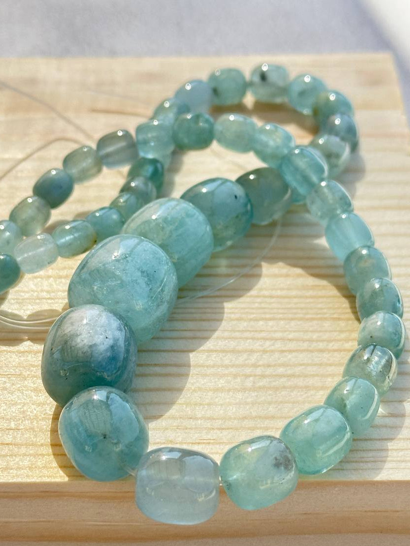 Teal graduated aquamarine beads on a light wooden surface