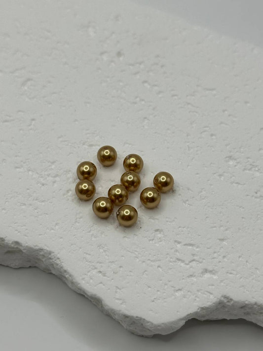 Bright gold crystal pearls on a textured white surface