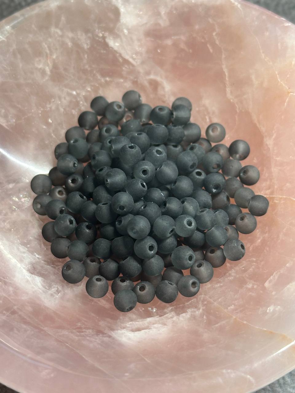 Dark gray beads on a translucent pink stone