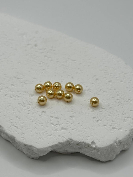 Gold crystal pearls on a textured white stone surface