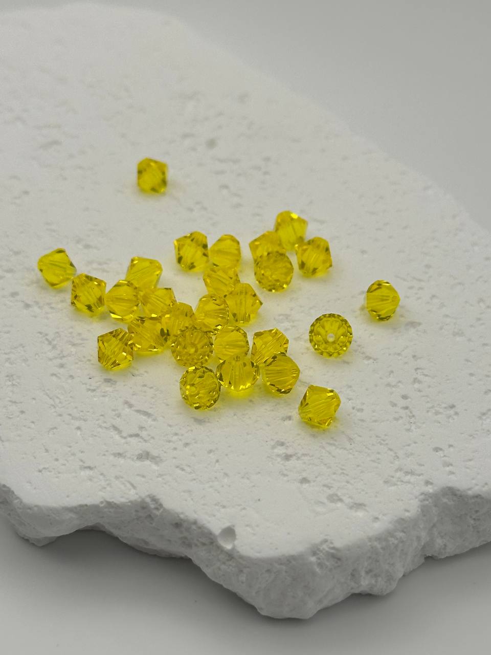 Yellow bicone beads on a textured white surface