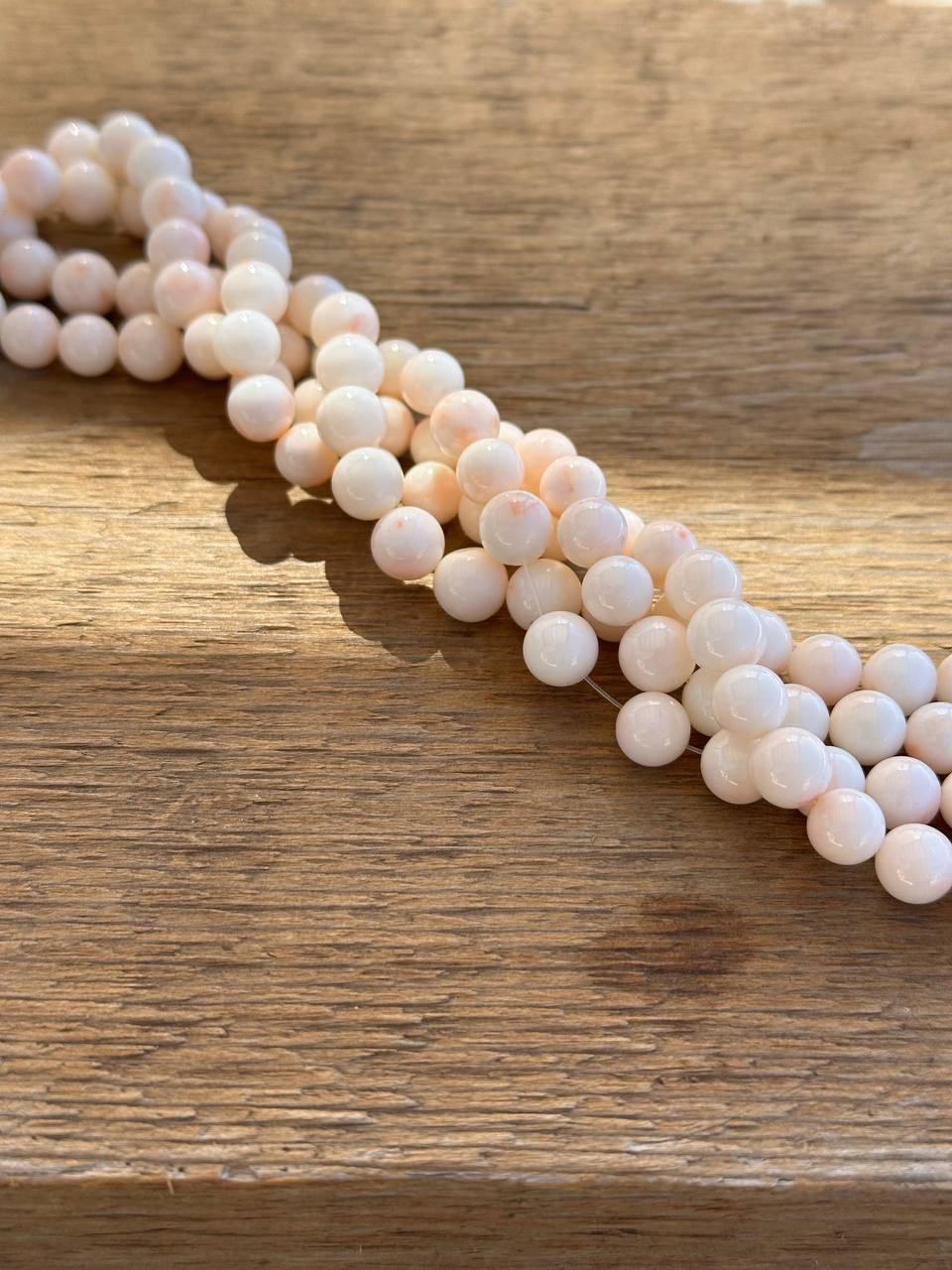 String of white and orange botswana agate beads on a wooden surface